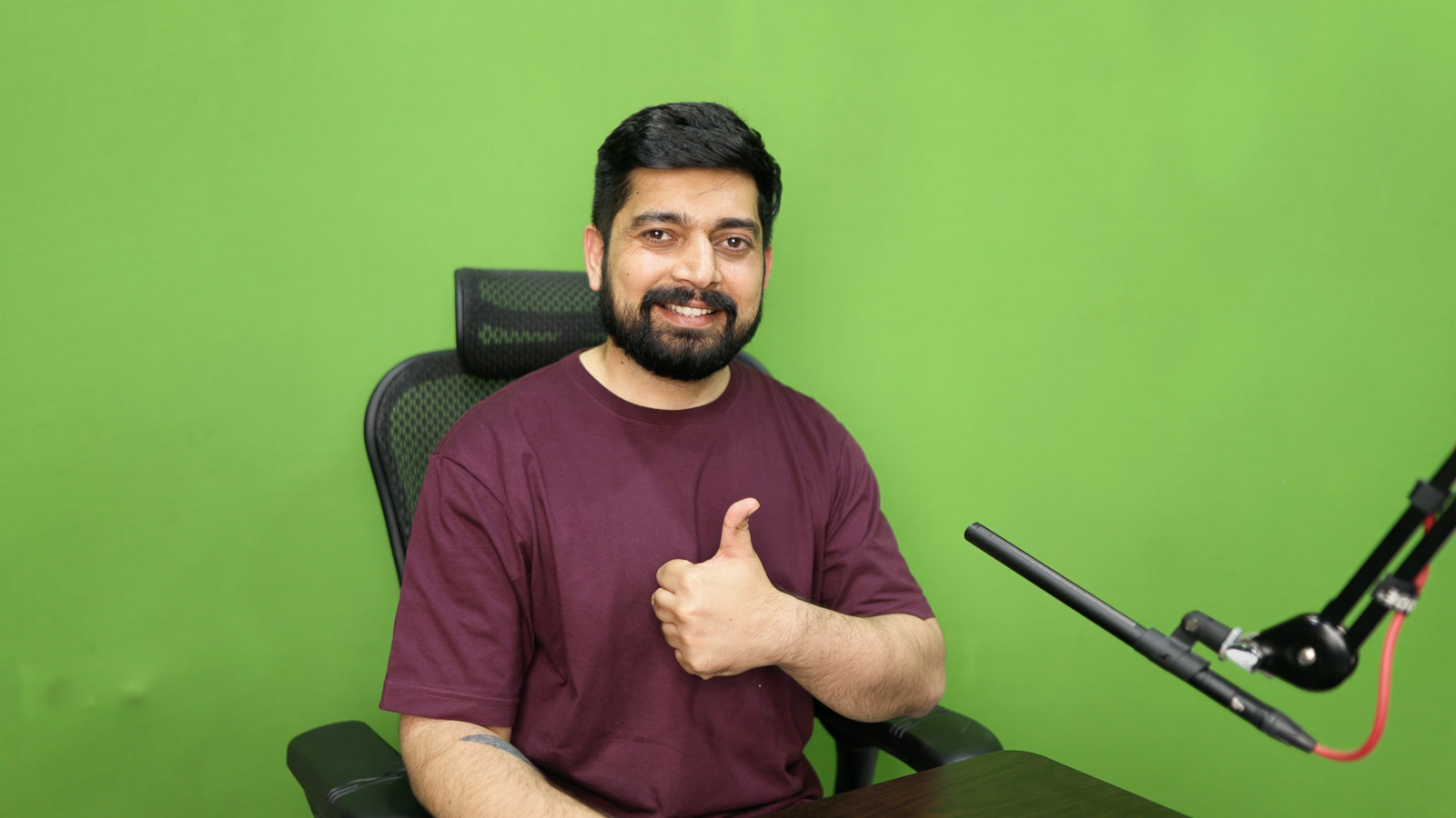 Raw camera frame: smiling, thumbs up, in front of a green screen